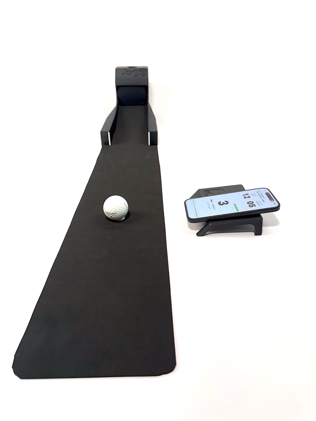 Head-on view down the mat with the docked phone alongside, showing the target Speed Number and putts remaining in the block