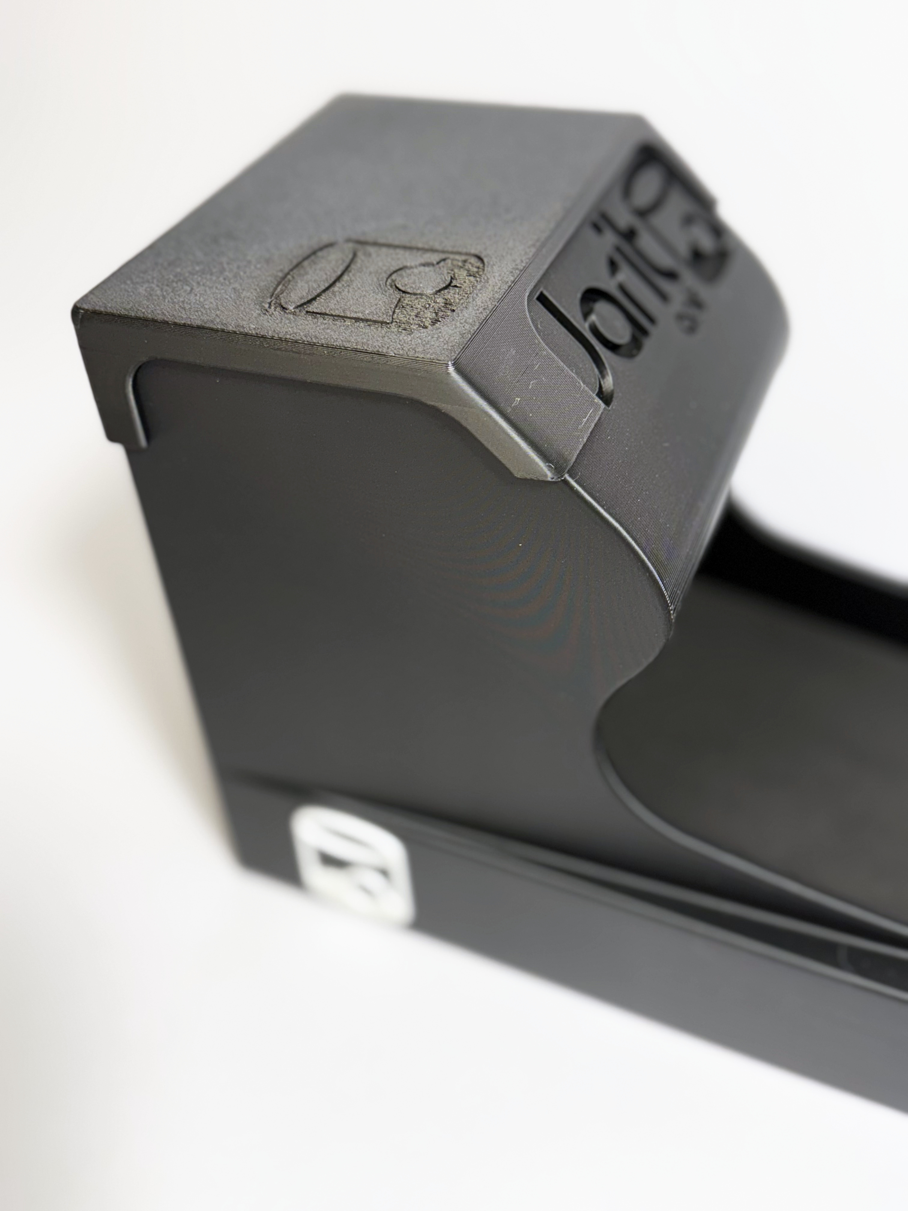 Close-up of the hood: the Jarit Golf wordmark and cup mark moulded into the matte-black print, the cup badge below